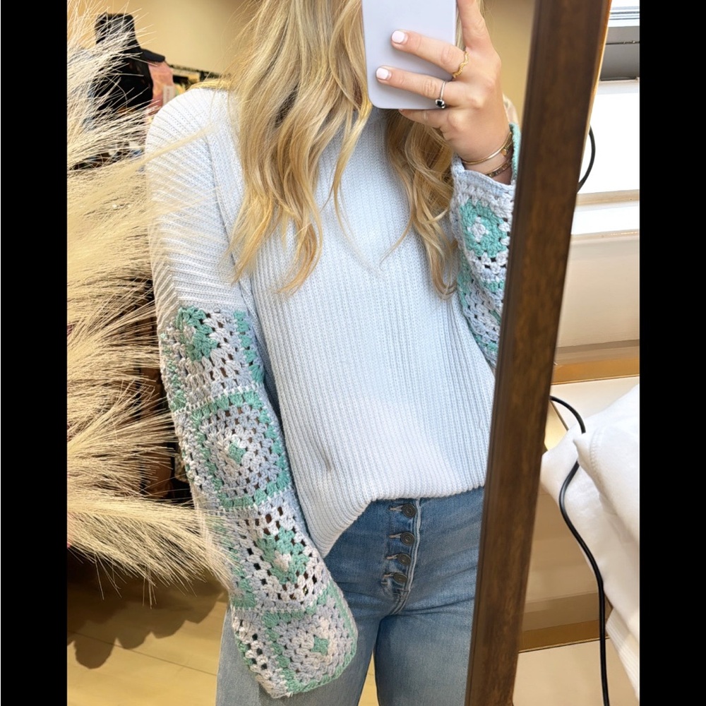 crotched detailing on the sleeves in purple and teal sweater